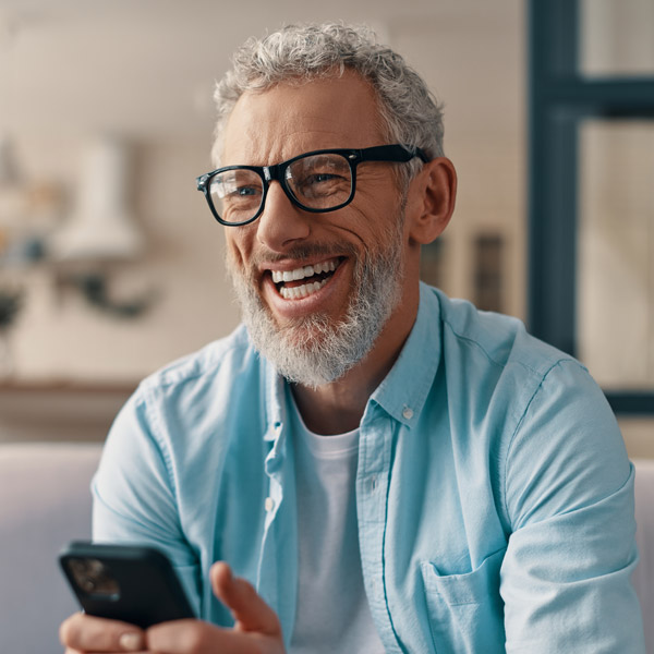 mature man smiling and holding phone